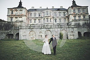 Beautiful fairytale newlywed couple hugging near old medieval castle