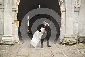 Beautiful fairytale newlywed couple hugging near old medieval castle