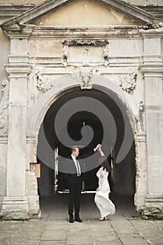 Beautiful fairytale newlywed couple hugging near old medieval castle