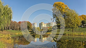 Beautiful fall colors reflect off a pond. Autumn park with high building