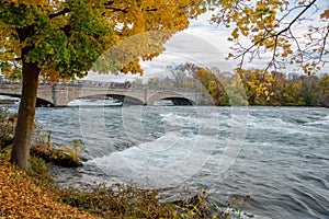 Beautiful fall foliage autumn leaves with Goat Island Bridge in Niagara Falls State Park, upstream of Niagara Falls waterfall at