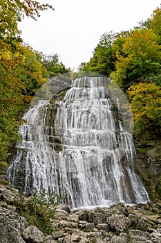 Beautiful fall forest landscape with idyllic waterfall and pool