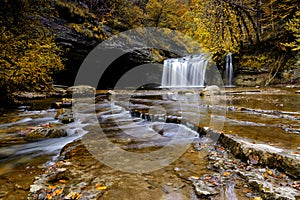 Beautiful fall forest landscape with idyllic waterfall and river
