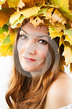 Beautiful fall woman. Portrait of girl with autumn wreath of maple leaves on head on isolated