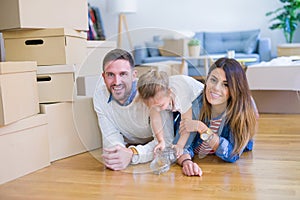 Beautiful famiily with kid lying down at new home around cardboard boxes