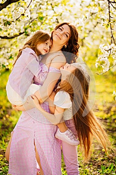 A family in a blossoming spring garden. Happy mom and two daughters.