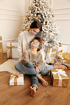 Beautiful family celebrating Christmas with decorated tree and presents