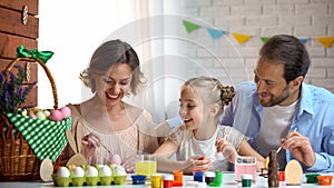 Beautiful family decorating Easter eggs with colorful paint, ancient traditions