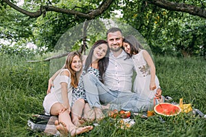 Beautiful family enjoying summer picnic at green garden