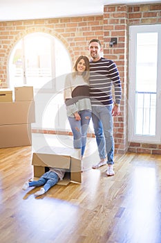 Beautiful family with a kid standing at new home around cardboard boxes