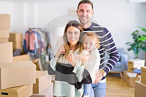 Beautiful family with a kid standing at new home around cardboard boxes