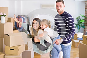 Beautiful family with a kid standing at new home around cardboard boxes