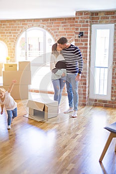 Beautiful family with a kid standing at new home around cardboard boxes