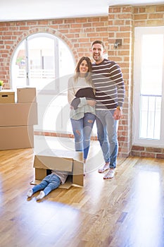 Beautiful family with a kid standing at new home around cardboard boxes