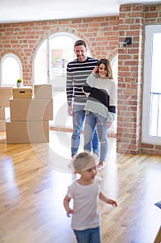 Beautiful family with a kid standing at new home around cardboard boxes