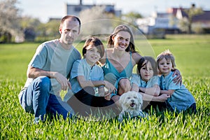 Beautiful family with kids, mom, dad, three boys and a dog, playing in the park