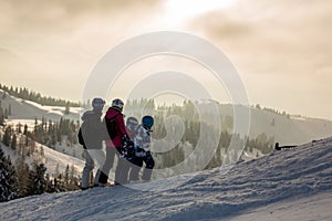 Beautiful family with kids, skiing in a scenery area in Austrian Alps on sunset, enjoying the view