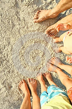 Beautiful family legs on the sand by the sea