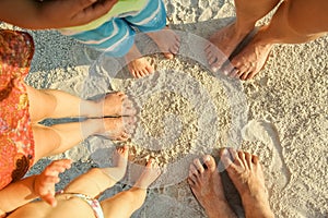 Beautiful family legs on the sand by the sea