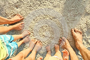 Beautiful family legs on the sand by the sea