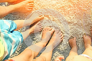 Beautiful family legs on the sand by the sea