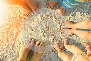 Beautiful family legs on the sand by the sea