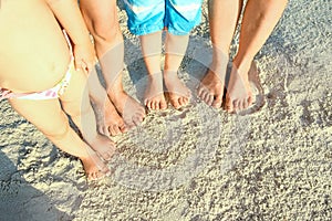 Beautiful family legs on the sand by the sea