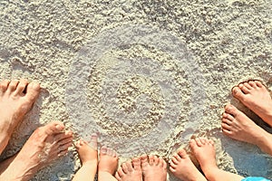 Beautiful family legs on the sand by the sea