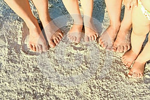 Beautiful family legs on the sand by the sea