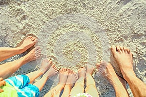 Beautiful family legs on the sand by the sea