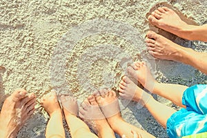 Beautiful family legs on the sand by the sea