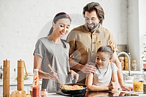beautiful family with little daughter cooking omelet