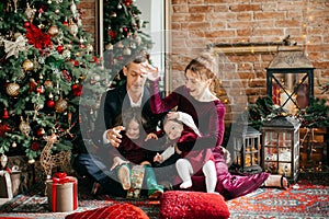 Beautiful family with little girls near a Christmas tree with gifts