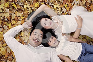 Beautiful family lying on autumn leaves