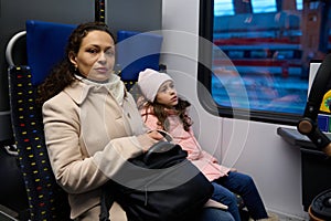 Beautiful family, mother daughter sitting by passenger window in a high speed train commuting from one city to other.