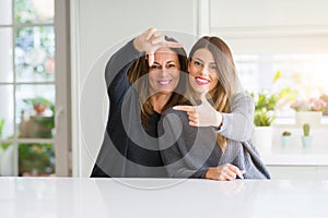 Beautiful family of mother and daughter together at home smiling making frame with hands and fingers with happy face