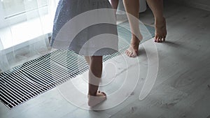 beautiful family mother and daughter in white dresses are sitting on the floor by large window