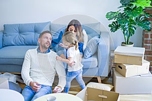 Beautiful family, parents sitting on the sofa drinking coffee looking his kid playing at new home around cardboard boxes