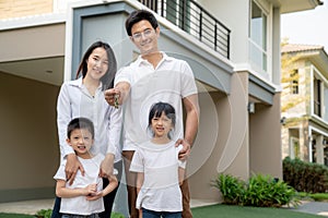 Beautiful family portrait smiling outside their new house with a key