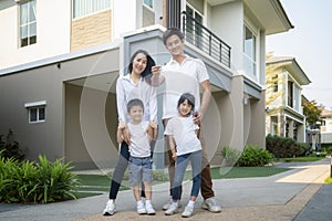 Beautiful family portrait smiling outside their new house with a key, this photo canuse for family
