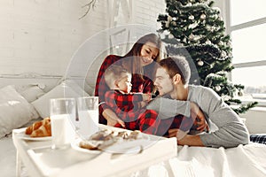 Beautiful family sitting on bed hugging and eating cookies