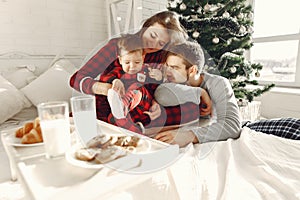 Beautiful family sitting on bed hugging and eating cookies