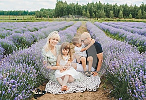 Beautiful family smiling while holding their kids in a lavender field during a sunny summer day