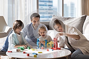 Happy family with kids playing wooden blocks at modern home