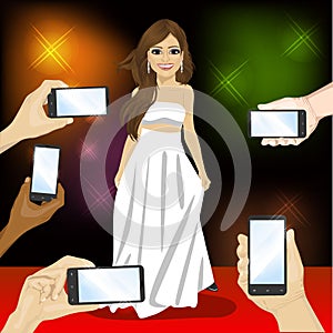 Beautiful famous woman posing on red carpet for people with smartphones