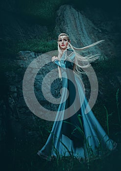 Beautiful fantasy woman elven goddess walks in nature mystical forest. Long creative vintage blue dress, sleeves. Blond