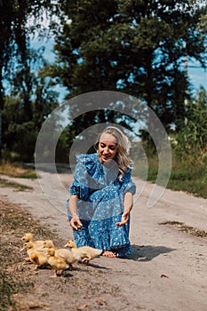 Beautiful farmer woman caring for little ducklings in the woods