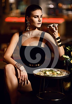 Beautiful fashion brunette woman in expensive interior restaurant eat oyster and lick one finger