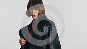 Beautiful fashion girl with bob hair and red lips posing on camera with serious look over white background