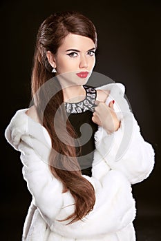 Beautiful fashion Lady in luxury fur coat and elegant black dress isolated on black background. Hairstyle. Makeup. Red Lips.